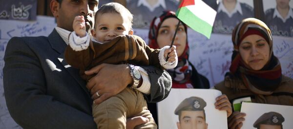 Familiares do piloto jordaniano executado pelo Estado Islâmico seguram cartazes com seu retrato - Sputnik Brasil