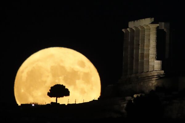 Lua surge no horizonte atrás das colunas do antigo Templo de Poseidon em cabo Sounion, cerca de 70 km de Atenas Lua surge no horizonte atrás das colunas do antigo Templo de Poseidon em cabo Sounion, cerca de 70 km de Atenas - Sputnik Brasil