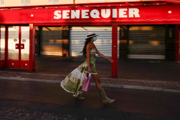 Mulher com máscara protetora caminha ao longo do Le Cafe Senequier, fechado, situado no porto de Saint-Tropez - Sputnik Brasil