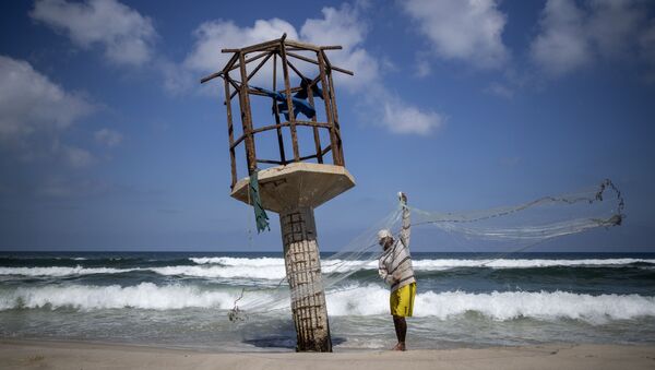 Um pescador palestino limpa sua rede de pesca em uma praia na cidade de Gaza - Sputnik Brasil