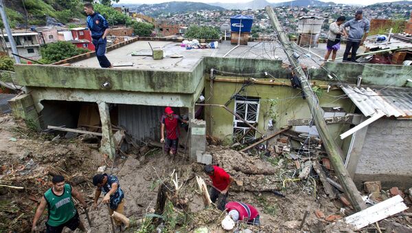 Moradores locais trabalham para limpar a lama e os escombros ao redor de casas destruídas - Sputnik Brasil