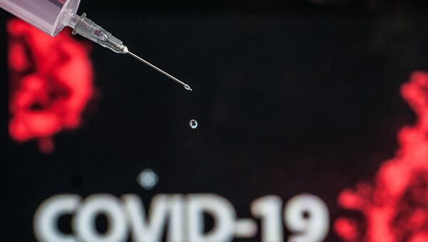 Uma seringa em alusão à vacina para o de combate ao Coronavírus (COVID-19), com uma representação do vírus ao fundo, fotografada nesta quarta-feira (15) na cidade do Rio de Janeiro.  - Sputnik Brasil