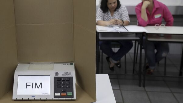 Em Brasília, uma urna eletrônica mostra a palavra Fim em uma seção eleitoral dois mesários ao fundo, em 28 de outubro de 2018. - Sputnik Brasil