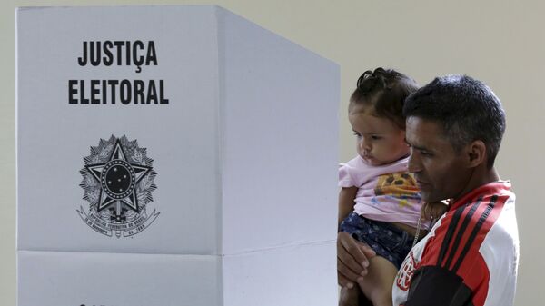 Eleitor com criança no colo chega a uma cabine eleitoral para registrar seu voto (foto de arquivo) - Sputnik Brasil