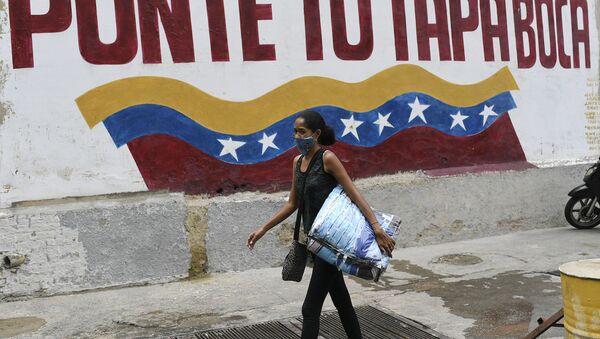 Mulher com máscara contra o coronavírus caminha em Caracas, na Venezuela, em frente a mensagem que diz: 'Coloque sua máscara' - Sputnik Brasil