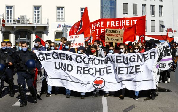 Em Konstanz, na Alemanha, policiais caminham ao lado de manifestantes contrários aos protestos que contestam as restrições sociais impostas pelo governo alemão em meio à pandemia da COVID-19, em 4 de outubro de 2020. - Sputnik Brasil