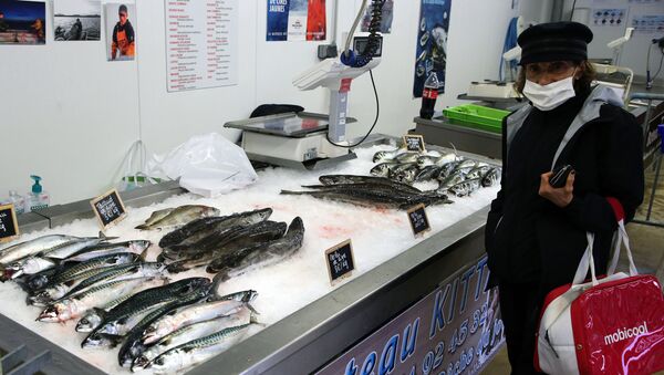 No porto de Cibourne, sul da França, uma mulher com máscara protetora contra a COVID-19 compra peixes em um barco pesqueiro, em 28 de abril de 2020 - Sputnik Brasil