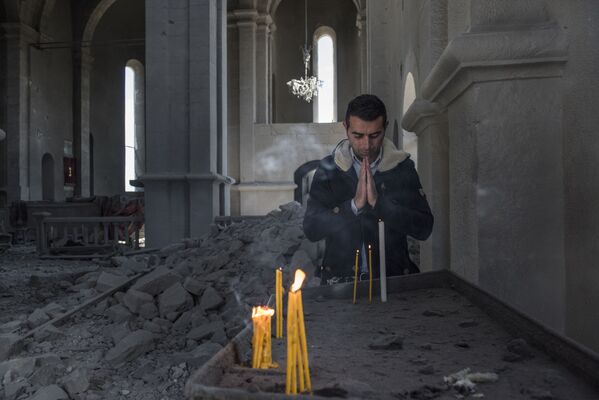 Homem reza em igreja destruída por bombardeio à cidade de Shusha, em Nagorno-Karabakh - Sputnik Brasil