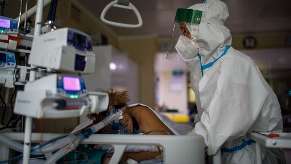 Медицинский работник оказывает помощь пациенту с COVID-19 в отделении реанимации и интенсивной терапии городской клинической больницы № 52 - Sputnik Brasil