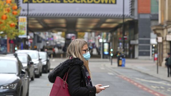 Mulher caminha com máscara para evitar contágio pelo coronavírus na cidade de Manchester, no Reino Unido - Sputnik Brasil