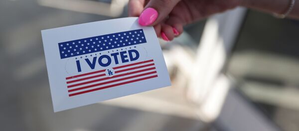 Pessoa exibe etiqueta Eu votei, enquanto cidadãos votam nas eleições do presidente dos EUA no primeiro dia de votação presencial alargada em meio à pandemia da COVID-19, em Los Angeles, Califórnia, EUA, 30 de outubro de 2020 - Sputnik Brasil