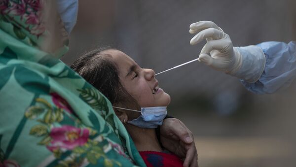 Agente sanitário efetua teste da COVID-19 em menina na Índia - Sputnik Brasil
