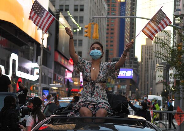 Moça levanta bandeiras dos EUA em Nova York após notícias anunciarem vitória do candidato democrata Joe Biden  - Sputnik Brasil