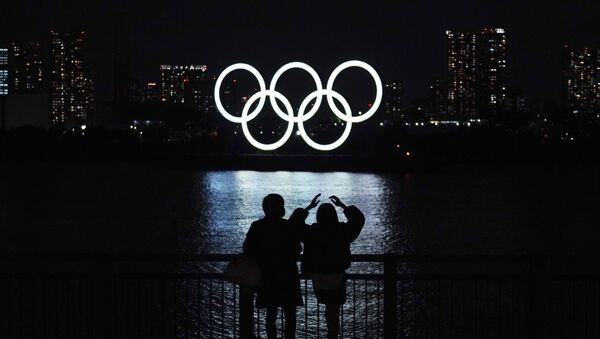 Pedestres olham os anéis olímpicos, iluminados na baía de Odaiba, em Tóquio, Japão, 1º de dezembro de 2020  - Sputnik Brasil