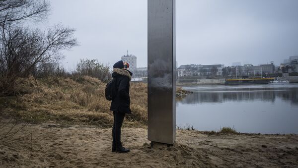 Mulher ao pé do monólito metálico que surgiu nas margens do rio Vístula, em Varsóvia, Polônia - Sputnik Brasil