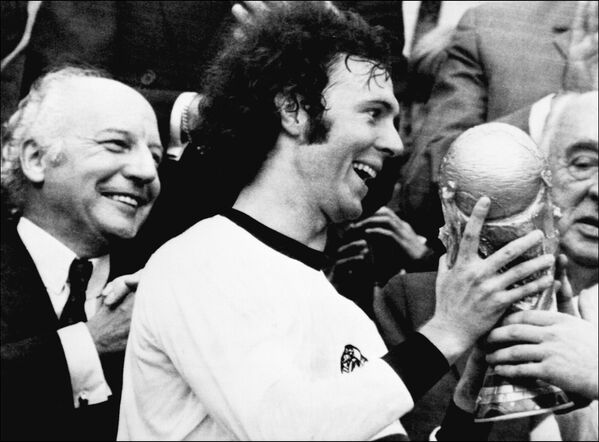 Jogador alemão e capitão da equipe, Franz Beckenbauer, recebe a taça da Copa do Mundo ganhada por seu time depois da vitória por 2 a 1 sobre Holanda em 7 de julho de 1974 no Estádio Olímpico de Munique, enquanto o presidente da Alemanha Ocidental, Walter Scheel, aplaude - Sputnik Brasil