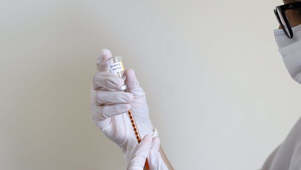 Foto ilustrativa com pessoa segurando seringa e tubo com vacina para a Covid-19 - Sputnik Brasil