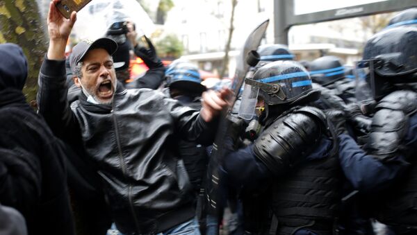 Agentes da polícia de choque atacam um homem que segura seu celular durante um protesto, 12 de dezembro, em Paris, França. Os protestos ocorrem contra uma proposta de lei que tornaria mais difícil para uma testemunha filmar policiais - Sputnik Brasil