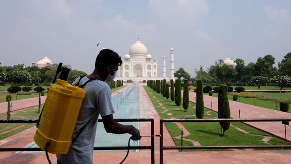 Funcionário de saúde higieniza corrimões tendo ao fundo o palácio Taj Mahal que foi reaberto em setembro de 2020 - Sputnik Brasil