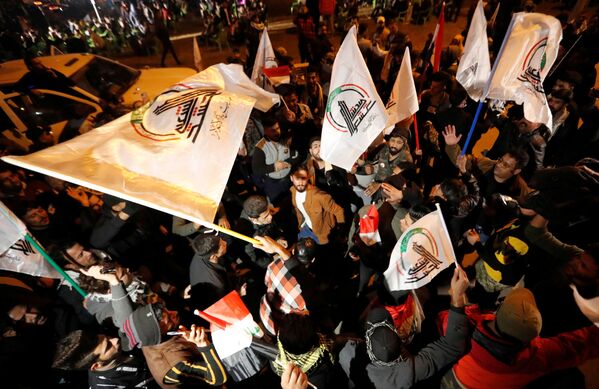 Pessoas levantam bandeiras durante o primeiro aniversário da morte do major-general iraniano Qassem Soleimani e do líder da milícia xiita iraquiana Abu Mahdi al-Muhandis em Bagdá, Iraque - Sputnik Brasil