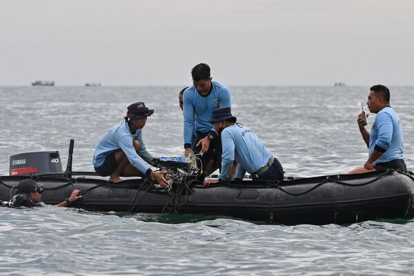 Mergulhadores da Marinha da Indonésia coletam destroços do avião de passageiros durante as operações de busca e salvamento - Sputnik Brasil