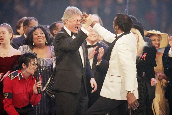 Presidente eleito Bill Clinton, à esquerda ao centro, dá um toque de cumprimento a Chuck Berry, à direita, durante o final da Gala Presidencial no Capital Centre em Landover, estado de Maryland, Estados Unidos, 19 de janeiro de 1993. À esquerda estão Michael Jackson, agachado, e Chelsea Clinton - Sputnik Brasil