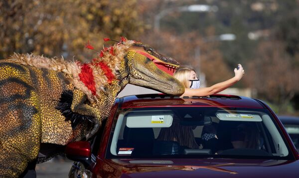 Menina tira selfie com um funcionário fantasiado de dinossauro, Califórnia, EUA, 15 de janeiro de 2021 - Sputnik Brasil