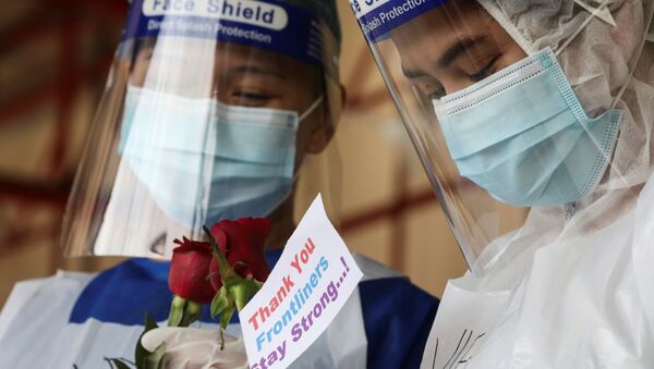 Profissionais de saúde seguram rosas oferecidas por cidadãos em um centro de testes para a COVID-19 na Malásia, 25 de janeiro de 2021 - Sputnik Brasil