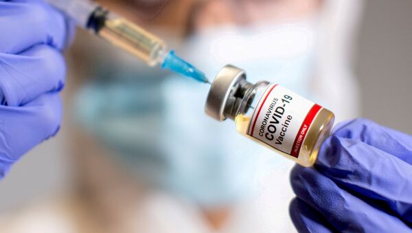 Profissional de saúde segura um frasco etiquetado com rótulo Vacina Coronavírus COVID-19 e uma seringa médica (foto de arquivo) - Sputnik Brasil
