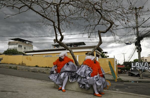 Dois homens de bate-bola sentados em subúrbio do Rio de Janeiro durante tradicionais celebrações do Carnaval no Brasil, apesar de estas terem sido canceladas devido à pandemia do coronavírus, 14 de fevereiro de 2021 - Sputnik Brasil