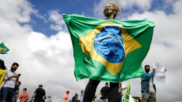 Mulher segura bandeira do Brasil em protesto contra medidas de combate à COVID-19, em Brasília, 1º de março de 2021  - Sputnik Brasil