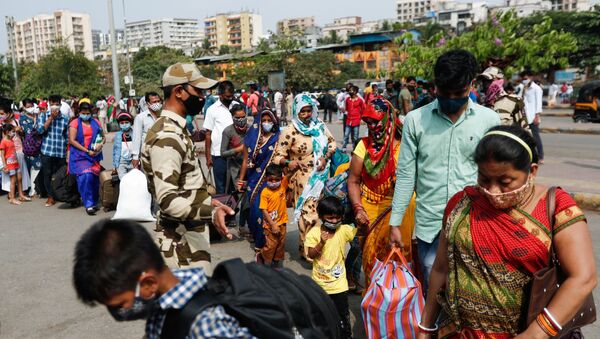 Pessoas usando máscaras protetoras caminham em fila em uma estação ferroviária em meio à disseminação da doença do coronavírus (COVID-19) em Mumbai, Índia, 9 de abril de 2021 - Sputnik Brasil