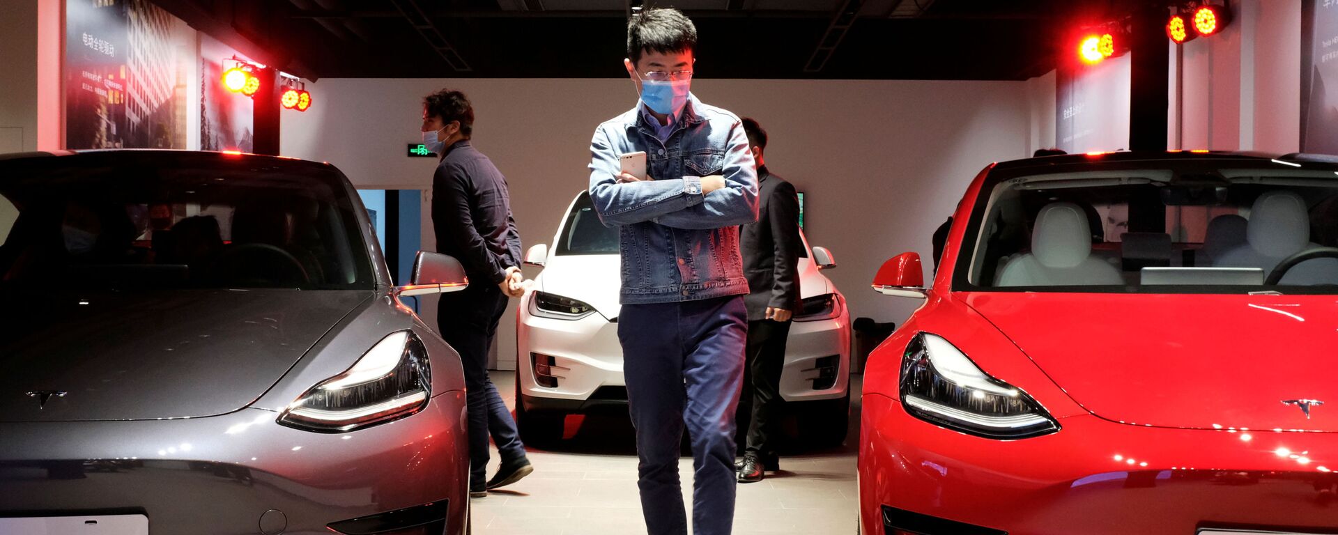 Homem observa carros Tesla Model 3 sedans e Tesla Model X esportivos em showroom da Tesla em Xangai, em maio de 2020 - Sputnik Brasil, 1920, 19.04.2021