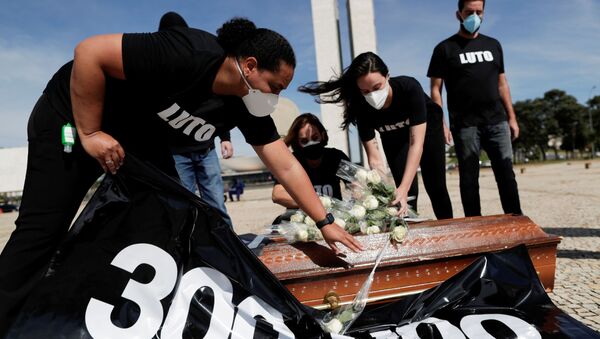 Profissionais de Saúde colocam flores em cima de um caixão para representar colegas mortos durante a pandemia, em protesto em Brasília, no Brasil, no dia 25 de março de 2021 - Sputnik Brasil