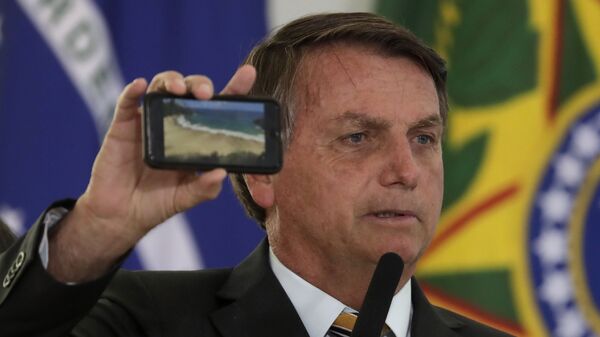Jair Bolsonaro mostra a foto de uma praia durante cerimônia de apresentação de um programa para reiniciar o turismo, em meio à pandemia de COVID-19, em 11 de novembro de 2020 - Sputnik Brasil