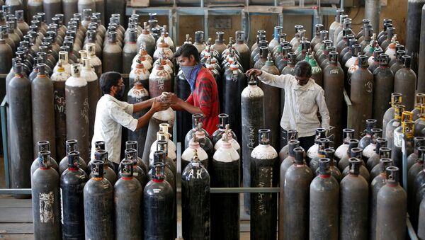 Em Ahmedabad, na Índia, pessoas carregam cilindros de oxigênio após enchê-los em uma fábrica em meio ao pico da pandemia da COVID-19 no país, em 25 de abril de 2021 - Sputnik Brasil