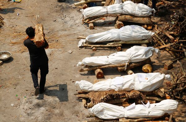 Em Nova Deli, na Índia, um homem carrega madeira para piras funerárias de cremação para corpos de pessoas infectadas com a COVID-19, em 26 de abril de 2021 - Sputnik Brasil