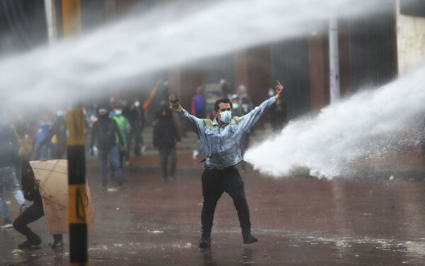 Manifestante faz gesto contra o canhão d’água da polícia durante os protestos antigovernamentais em Bogotá, Colômbia, 5 de maio de 2021 - Sputnik Brasil
