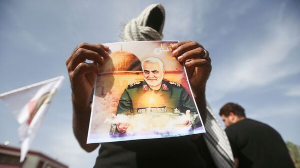 Membro das Unidades de Mobilização Popular do Iraque (PMU, na sigla em inglês) mostra foto de Qassem Soleimani, general iraniano assassinado em 3 de janeiro de 2020, em Basra, Iraque, 7 de maio de 2021 - Sputnik Brasil