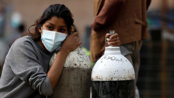Em Kathmandu, na Índia, uma mulher segura cilindros de oxigênio após abastecê-los em uma fábrica, em 9 de novembro de 2021 - Sputnik Brasil