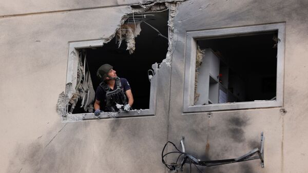 Especialista do esquadrão antibombas da polícia de Israel na janela de um prédio residencial danificado após ser atingido por um foguete lançado da Faixa de Gaza, 11 de maio de 2021. - Sputnik Brasil