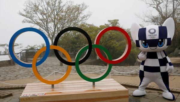 O mascote dos Jogos Olímpicos de Tóquio, Miraitowa, posa ao lado símbolo olímpico, em Tóquio, no Japão, no dia 14 de abril de 2021 - Sputnik Brasil