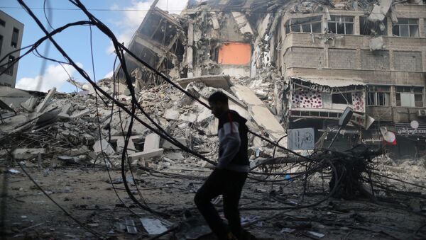 Homem caminha em frente à prédio destruído em ataque aéreo israelense contra a Faixa de Gaza - Sputnik Brasil