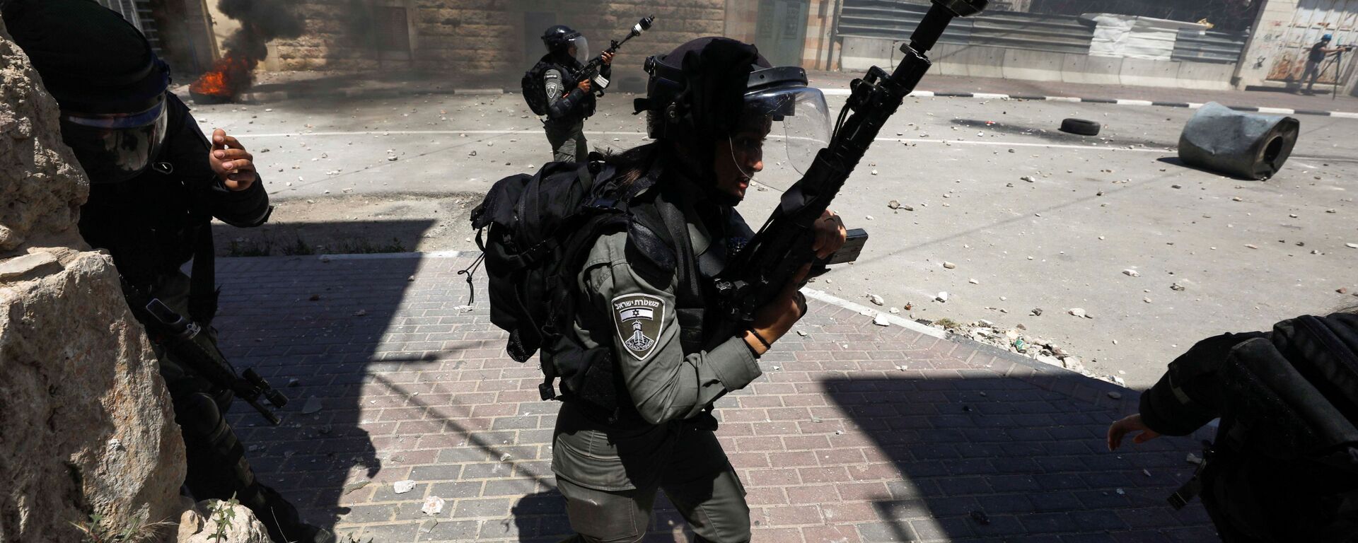 Membros da polícia israelense caminham enquanto palestinos protestam contra a tensão em Jerusalém e a escalada Israel-Gaza, em Hebron, na Cisjordânia ocupada por Israel, 14 de maio de 2021 - Sputnik Brasil, 1920, 13.07.2021