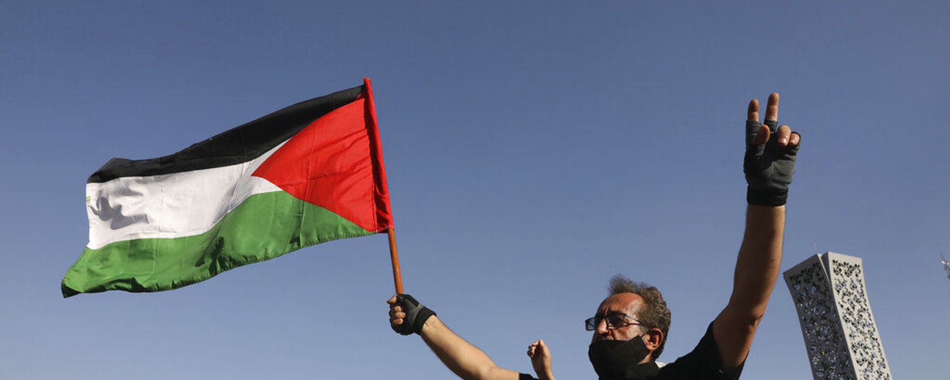 Manifestante segura bandeira palestina enquanto faz sinal da vitória em Teerã, no Irã - Sputnik Brasil, 1920, 03.06.2024