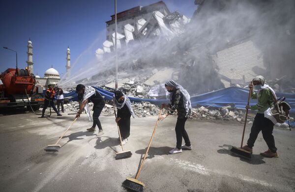 Voluntários e trabalhadores municipais palestinos limpam os escombros do complexo Hanadi, destruído por um ataque aéreo israelense, na Faixa de Gaza, 25 de maio de 2021 - Sputnik Brasil