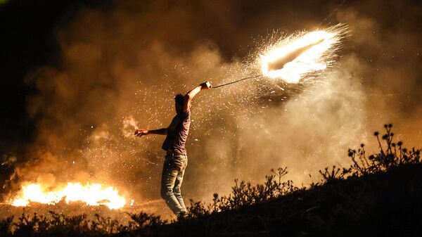 Manifestante palestino joga foguete em chamas contra forças de Israel durante manifestação a leste da Cidade de Gaza, na fronteira com Israel, 15 de junho de 2021. - Sputnik Brasil