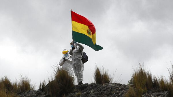 Profissionais de saúde com equipamentos de proteção completos para conter a propagação do novo coronavírus hasteam bandeira boliviana nos arredores de Choquecota, Bolívia. Foto de arquivo - Sputnik Brasil