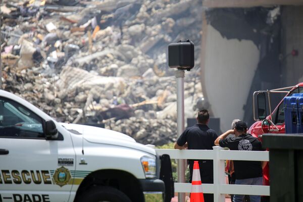 Socorristas olham para os escombros do edifício residencial, enquanto as equipes de emergência continuam as operações de busca e resgate de sobreviventes em Surfside, perto de Miami Beach, Flórida, EUA, 26 de junho de 2021 - Sputnik Brasil