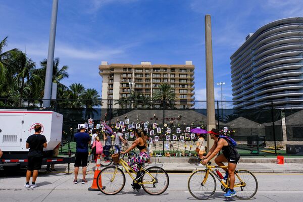 Pessoas olham para o espaço memorial criado por vizinhos em frente do edifício parcialmente destruído em Surfside, perto de Miami Beach, Flórida, EUA, 26 de junho de 2021 - Sputnik Brasil